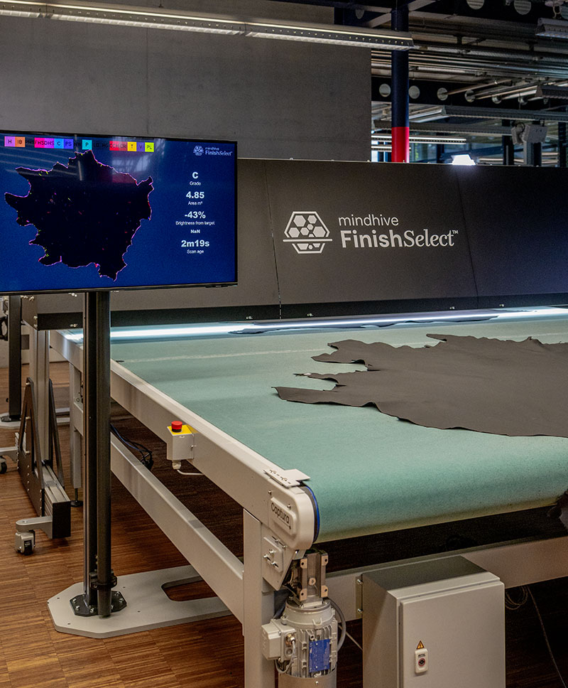 Mindhive FinishSelect™ system scanning finished leather with real-time defect map, grade, and area data displayed on screen